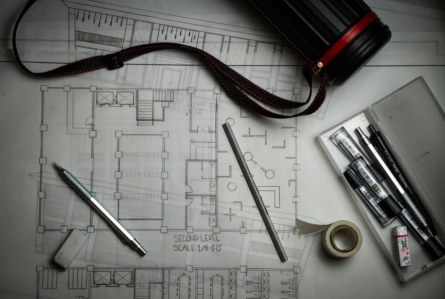 Architectural blueprints with drafting tools and a tape measure.