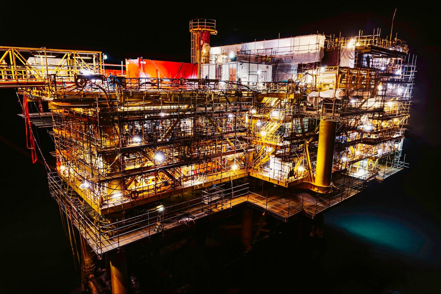 An illuminated offshore platform at night.